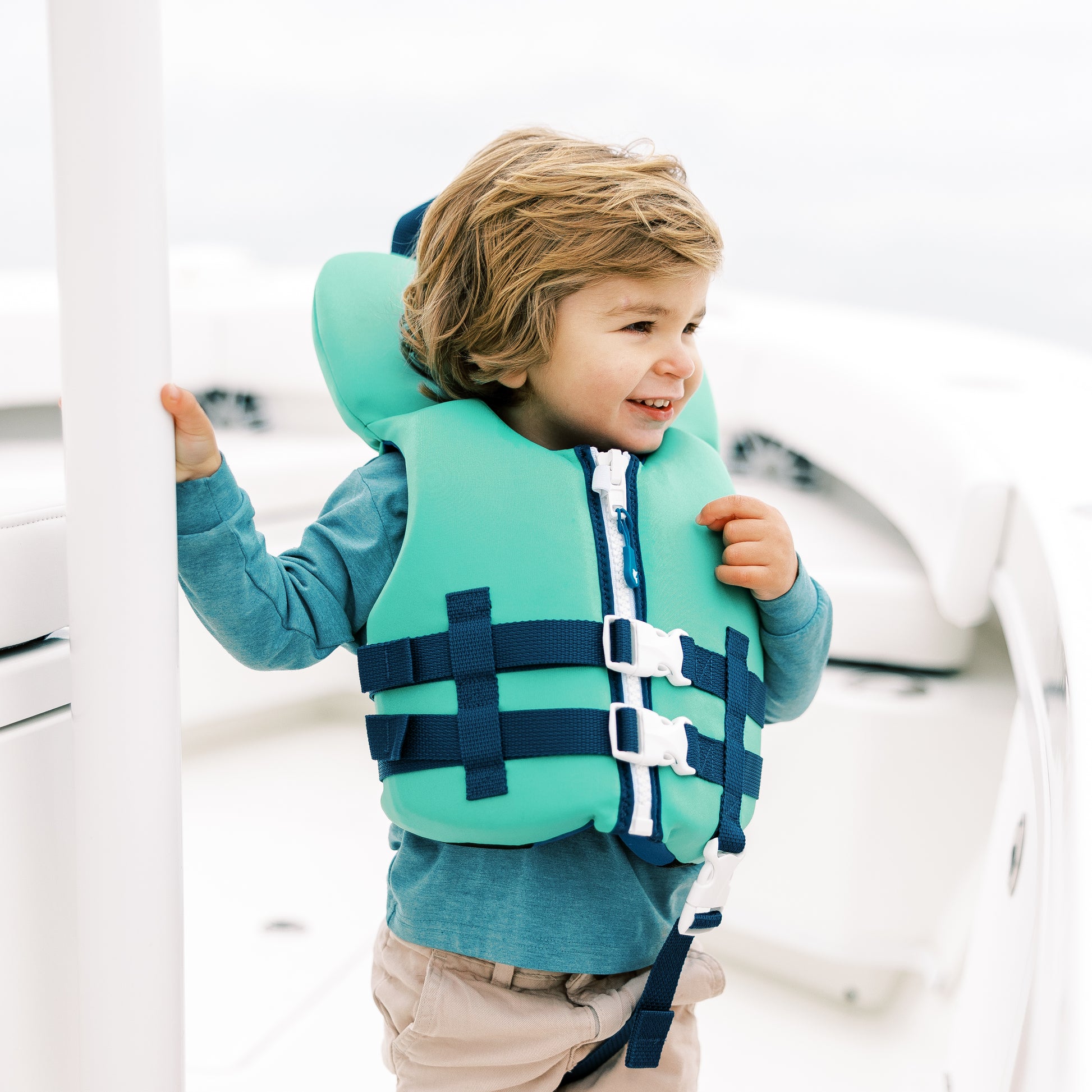 Child wearing a green life jacket on a boat